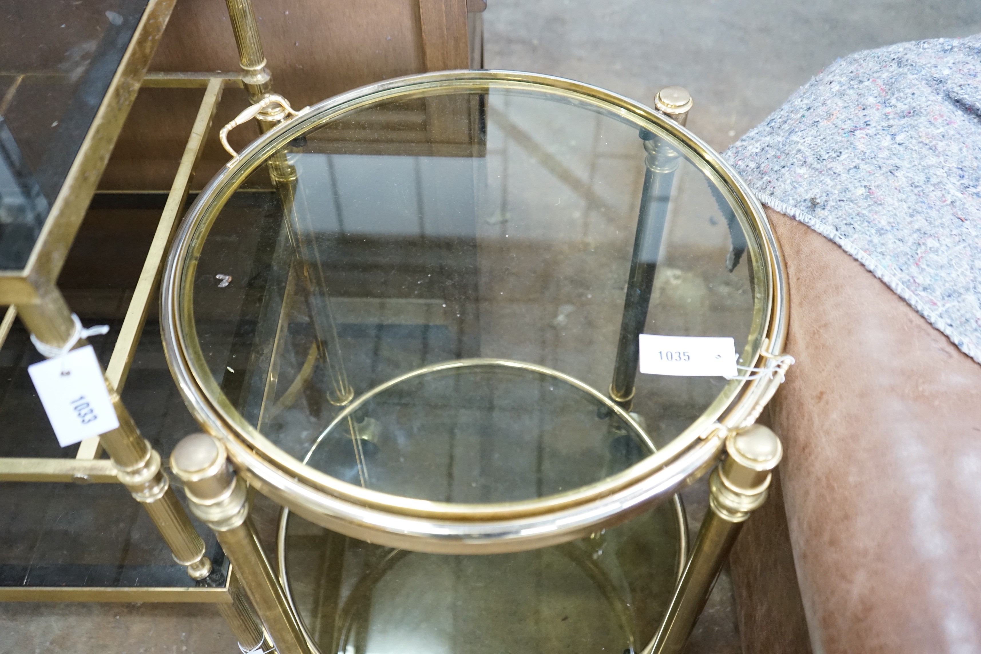 A circular smoked glass and brass tray top two tier occasional table, diameter 57cm, height 64cm